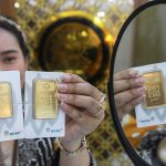 Seorang wanita menunjukkan emas Antam di Galeri 24, Jakarta, Selasa (21/5/2024). (Foto: Bloomberg Technoz/Andrean Kristianto)