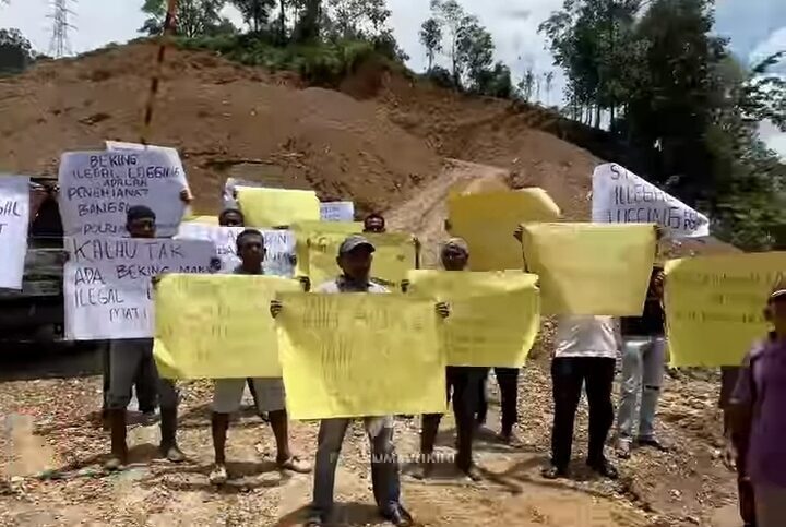 Warga Tanjung Balik membawa poster penolakan illegal logging saat aksi di tepi Jalan Sumbar-Riau, Kamis (2/10/2025). (Screenshot @payakumbuhkini)
