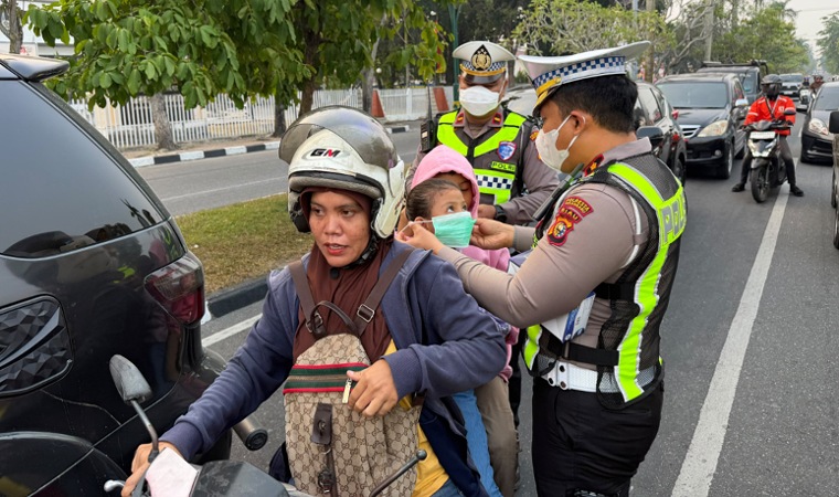 Satlantas Polresta Pekanbaru membagikan ribuan masker kepada pengendara di tengah kondisi kabut asap yang menyelimuti Kota Pekanbaru, Riau. (Defizal)